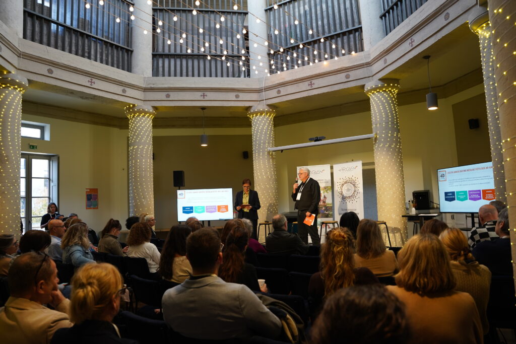 Conférence APOGÉES avec intervenants et public dans une salle décorée de guirlandes lumineuses
